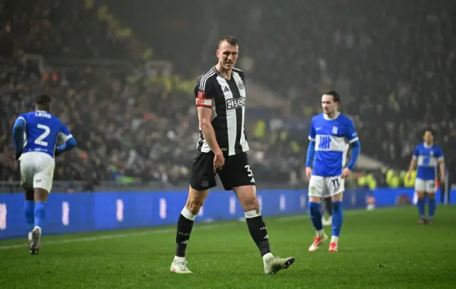 Dan Burn of Newcastle United reacts, while holding his leg