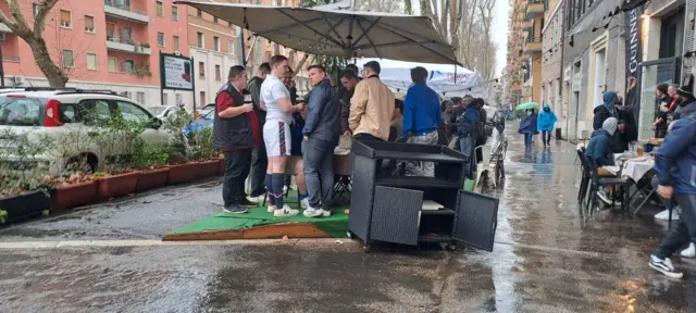 Fans gather under a canopy for rain cover in Rome