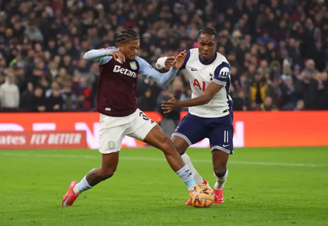 Leon Bailey of Aston Villa battles for possession with Mathys Tel of Tottenham