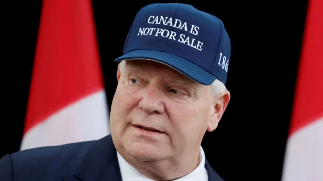 Doug Ford wearing a suit and tie and a hat that says Canada is not for sale