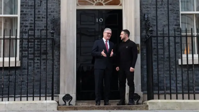 Keir Starmer (L) and Volodymyr Zelensky (R) talk outside the main door of No 10 as photographers take pictures