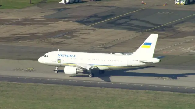 Plane with yellow and blue stripes on an airport runway.