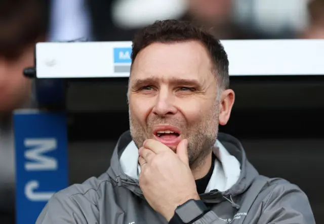 John Eustace puts his hands to his face in a pensive manner in his dug out