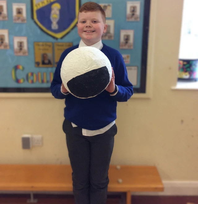 Child holding a homemade astronaut helmet .