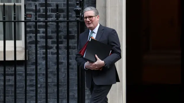 Starmer walks away from the door at Number 10 while clutching a set of folders