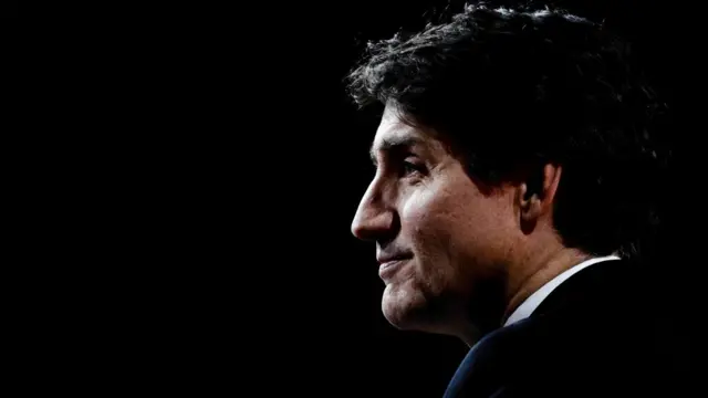 Trudeau looks on in close up, his face slightly silhouetted
