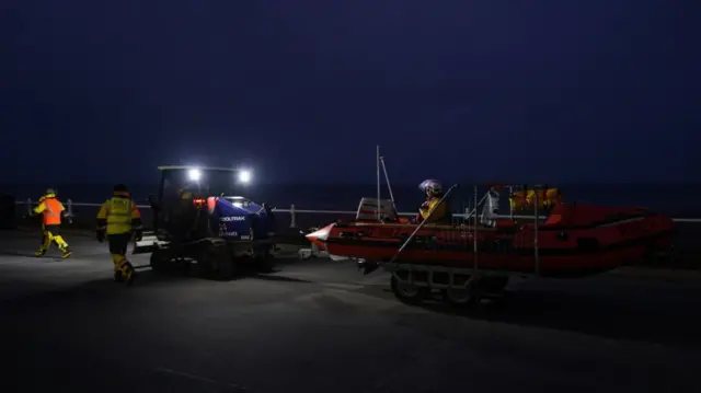 A lifeboat being pulled by another vehicle on shore