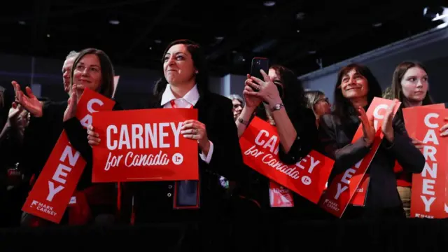 People holding posters react on the day former Bank of Canada and Bank of England governor Mark Carney won the race to become leader of Liberals. The signs read: Carney for Canada