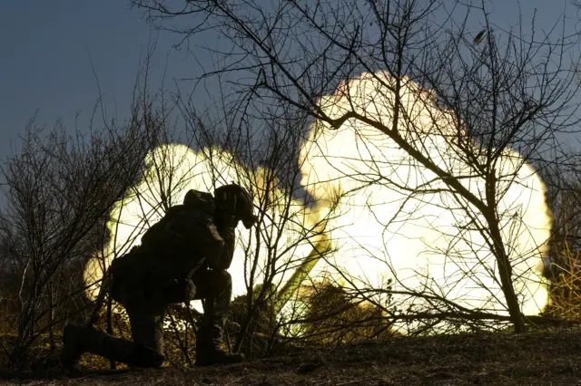 A Ukrainian soldier fires as howitzer towards Russian troops