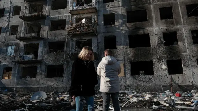 People look at a damaged building two days after a Russian shelling in Dobropillya, Donetsk, Ukraine