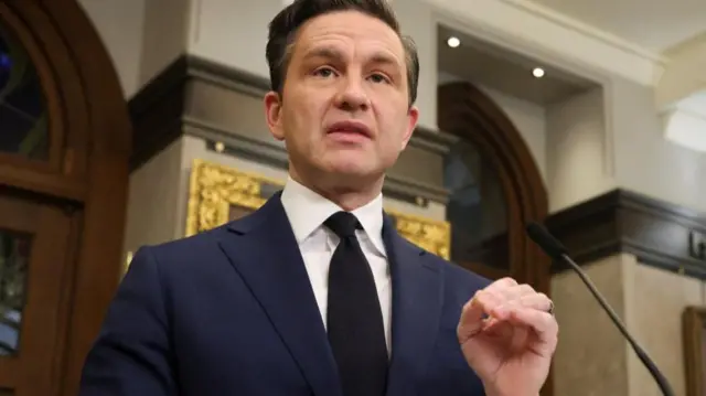 Pierre Poilievre speaks at a lectern while gesturing with his hand
