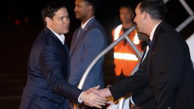 U.S. Secretary of State Marco Rubio greets members of the crew as he boards airplane