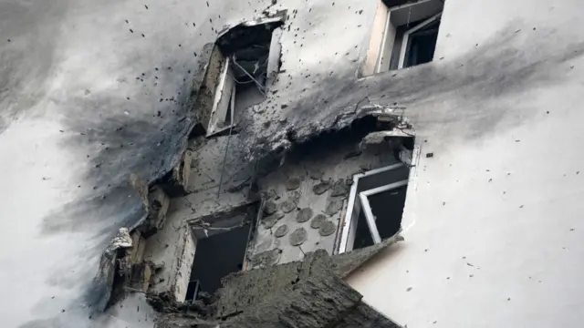 The aftermath of a drone attack on a residential building, with broken windows.