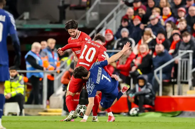 Alexis Mac Allister of Liverpool FC and Khvicha Kvaratskhelia of PSG battle for the ball.