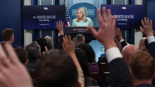 Hands are raised as White House Press Secretary Karoline Leavitt speaks to members of the media