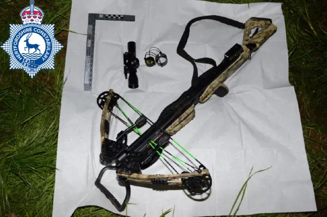 A khaki crossbow laid on a white sheet