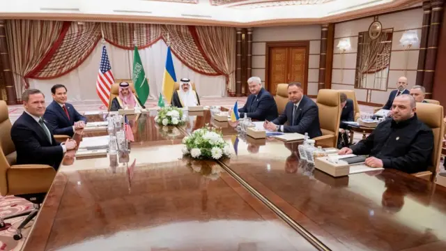 Saudi Foreign Minister Faisal bin Farhan (left) and National Security Advisor Mosaad bin Mohammad Al-Aiban are seated at the head of a large table, with US and Ukrainian officials.