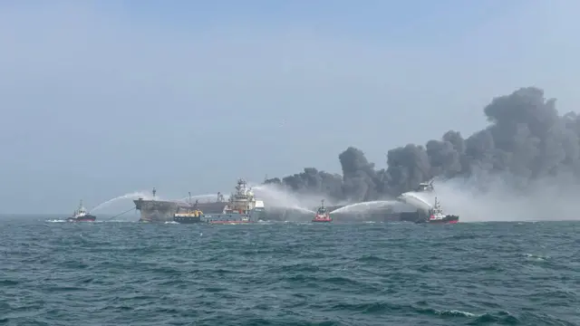 Firefighting ships spray water on the two burning ships