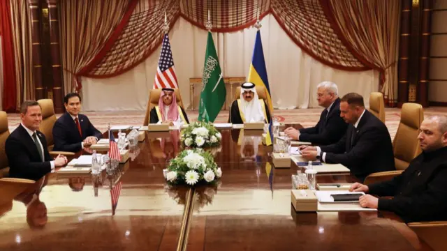 The delegates and Saudi hosts sit around a wooden table