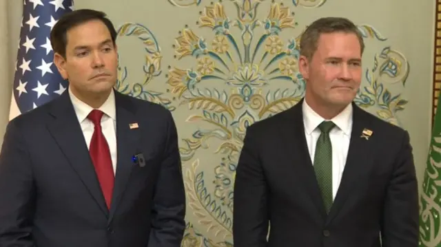 Rubio and Waltz stood next to each other looking in one direction with serious faces