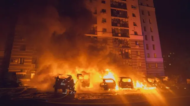 Burning cars and a damaged building