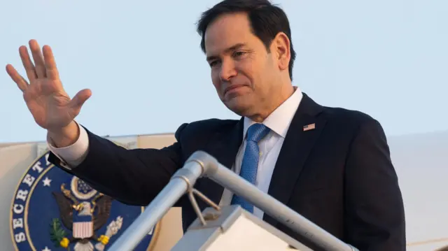 Marco Rubio, US Secretary of State, waves from the steps of a plane