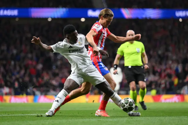Vinicius Junior of Real Madrid is challenged by Marcos Llorente of Atletico de Madrid.
