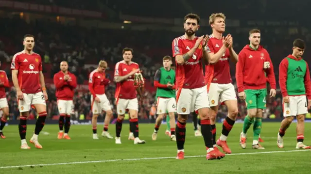 Manchester United players applauding the fans at Old Trafford.