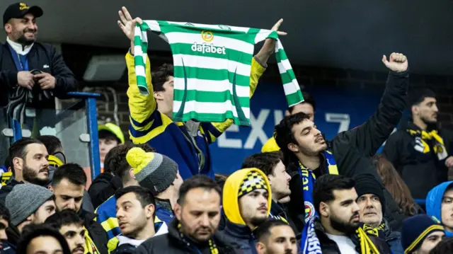 A Fenerbahce fan holds a Celtic top in the air at Ibrox