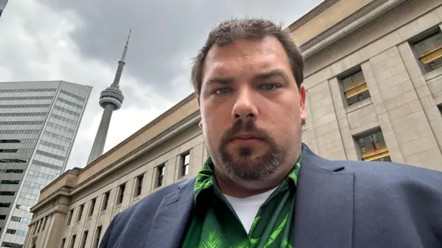 James Somaeck looks at the camera in front of a building.