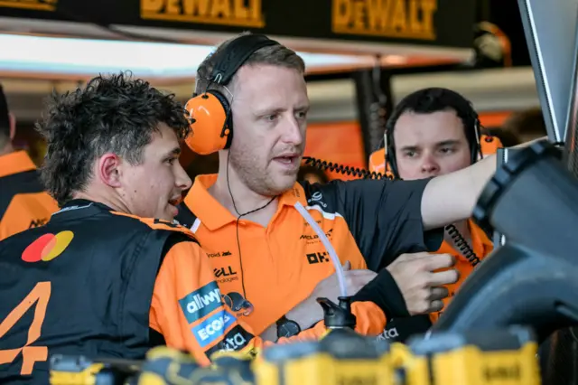 Lando Norris speaks to a McLaren crew member