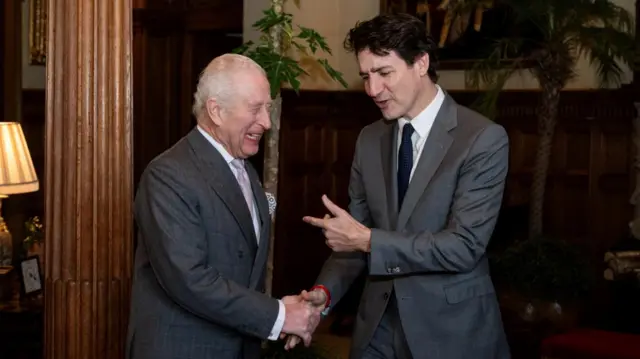 King Charles III laughs as he shakes hands with outgoing Canadian prime minister Justin Trudeau.