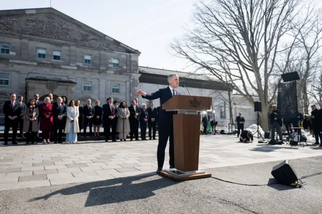 Mark Carney gives a speech outside Rideau Hall, with his cabinet stood in line behind him