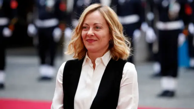 Giorgia Meloni wears a white shirt and black waistcoat