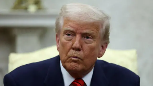 Trump looks ahead, wearing a suit, in the Oval Office.