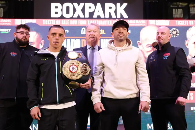 Nick Ball holds the WBA featherweight title over his shoulder and stands next to TJ Doheny at a news conference