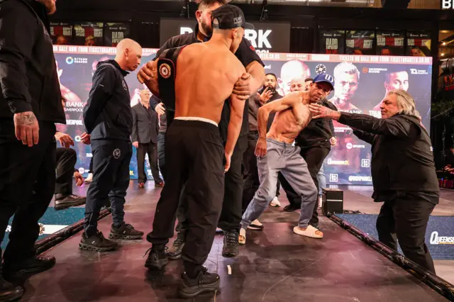 Nick Ball and TJ Doheny are held apart by security on a stage at a weigh-in