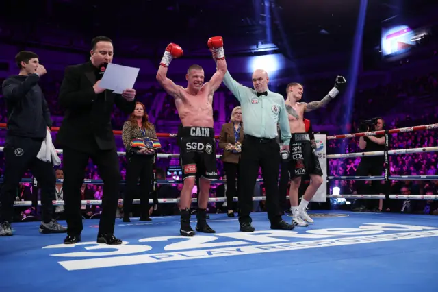 Andrew Cain has his hand raised by the referee with Charlie Edwards upset beside him