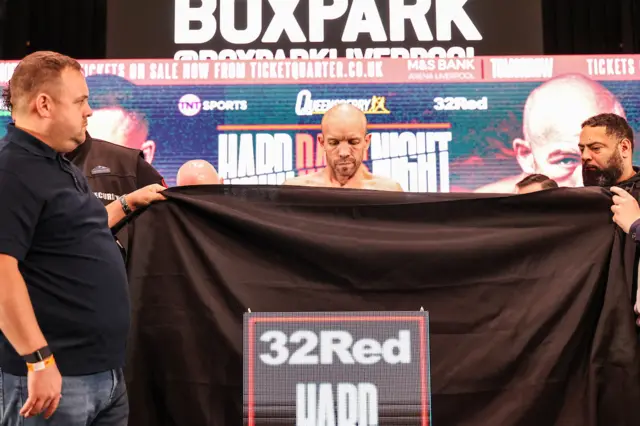 TJ Doheny stands behind a black sheet as he stands on stage to weigh-in