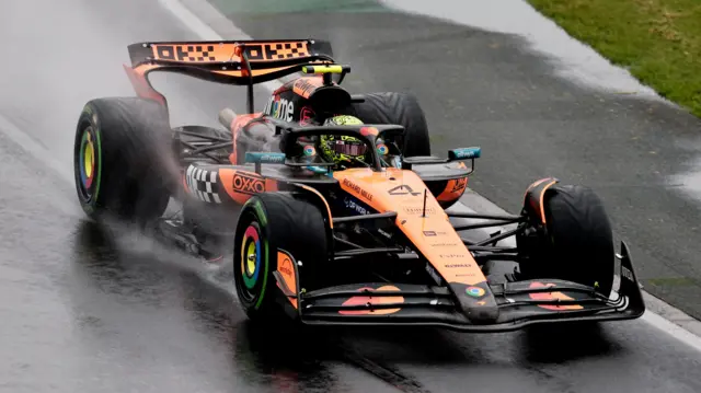 McLaren's Lando Norris drives his McLaren to the grid in wet conditions before the Australian Grand Prix