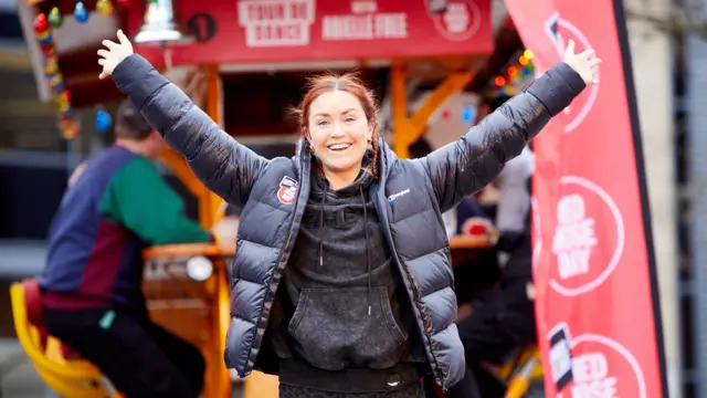 Arielle Free smiling with her arms in the air, celebrating completing her Comic Relief challenge