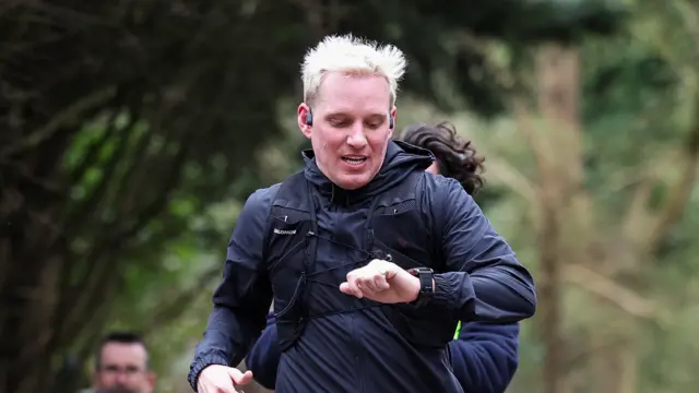 Jamie checks his watch as he runs