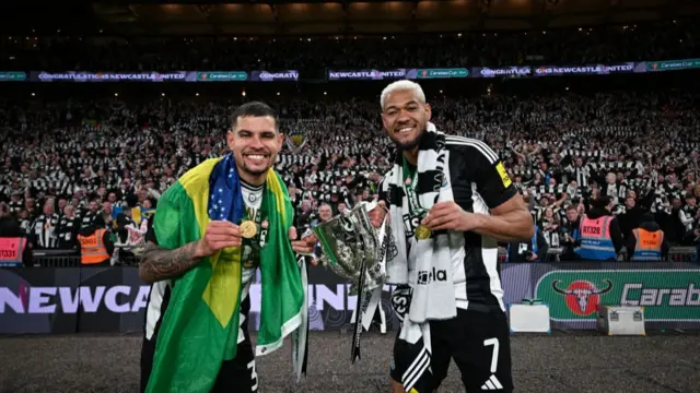 Joelinton and Bruno Guimares with the Carabao Cup in front of the Newcastle fans