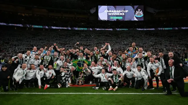 Newcastle pose with the cup in front of fans