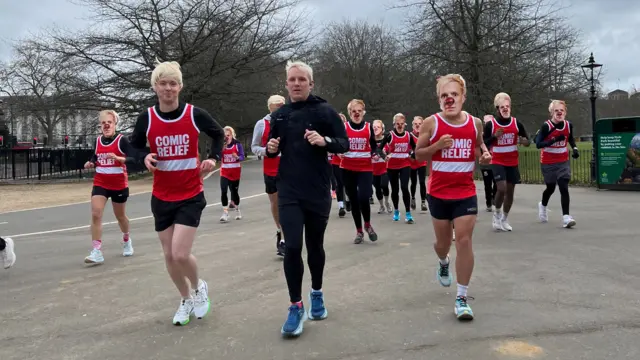 A sea of peroxide blonde - Jamie Laing is joined by Radio 1's Sam MacGregor, plus 49 other lookalikes, for a kilometre of his Ultra Marathon Challenge. They all wear Jamie Laing masks and blonde wigs.