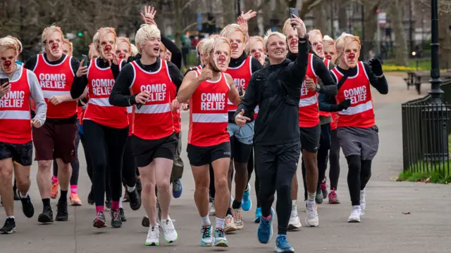 Jamie Laing takes a selfie with a group of runners dressed up as him.