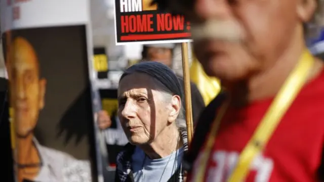 An elderly woman holds up a sign that calls on the Israeli government to bring home one of the hostages still in Gaza