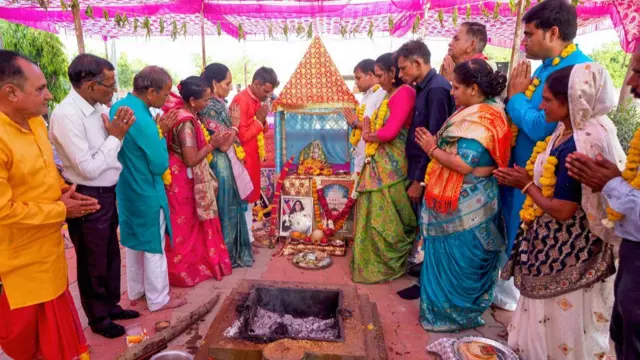People in bright clothing praying and displaying pictures of the astronauts