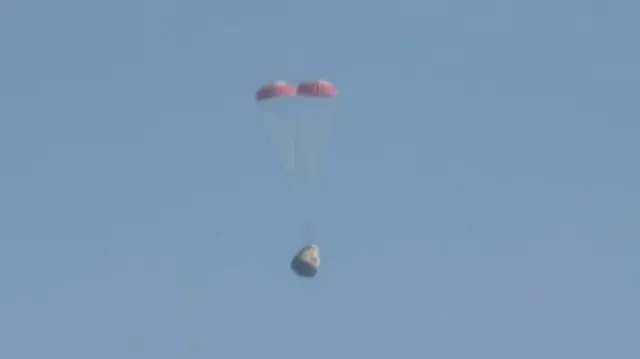 Two parachutes above the dragon capsule in a blue sky