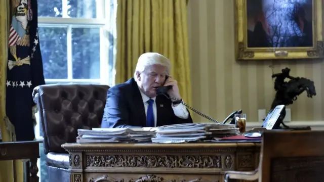Donald Trump speaking on the phone to Putin from his desk in the Oval Office.
